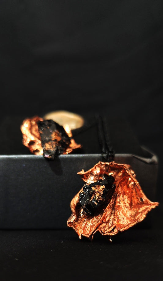 Mistična verižica z obeskom iz premoga ter pravim listom vrtnice- ujete za večno v baker. Posebna in neobičajna verižica za vse, ki jim stik z naravo in estetika daje smisel. Vsak list vrtnice je bil posebej izbran - na voljo je le 3 verižice, velikost se določi glede na velikost kamna. Verižica velikosti S ima črno verigo, M - verigo srebrne barve ter L v barvi temno siva.