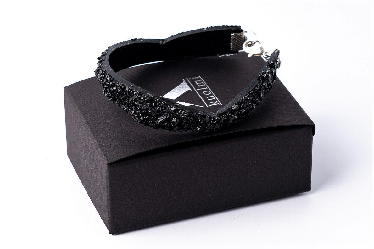 The KUOLMi Black bracelet is made of 10 million-year-old coal. Due to its black luster and special organic shape, each piece is unique and unrepeatable in its appearance. This bracelet will instantly upgrade your styling. A statement piece that combines edgy attitude and high fashion.