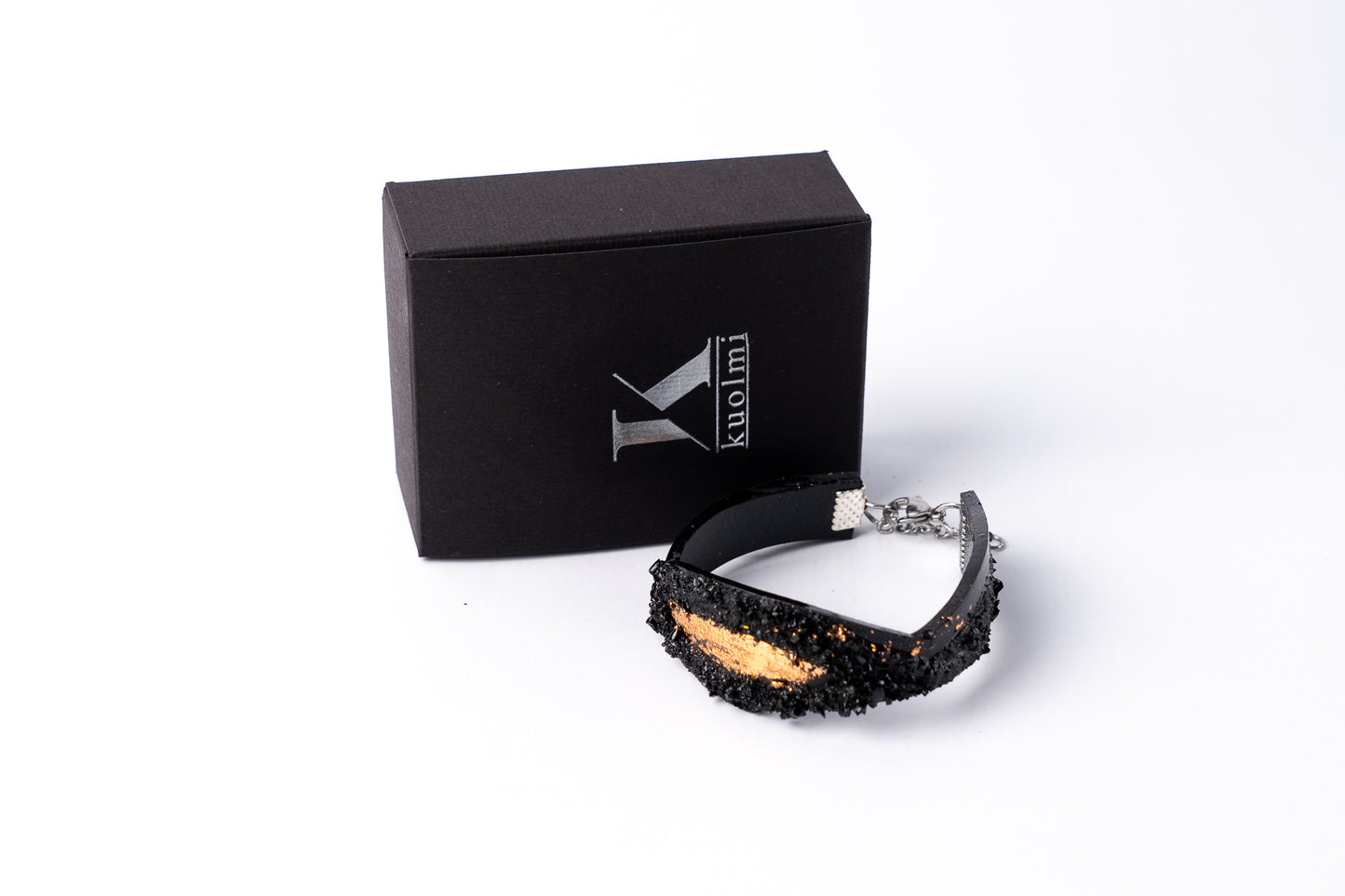 The KUOLMi Rosegold bracelet is made of 10 million-year-old stone. Due to its black luster and special organic shape, each piece is unique and unrepeatable in its appearance. It is made entirely by hand from coal and stainless steel. The size is adjustable. Jewelry is packaged in a gift box. The story about coal from which the bracelet was made is included as a gift.