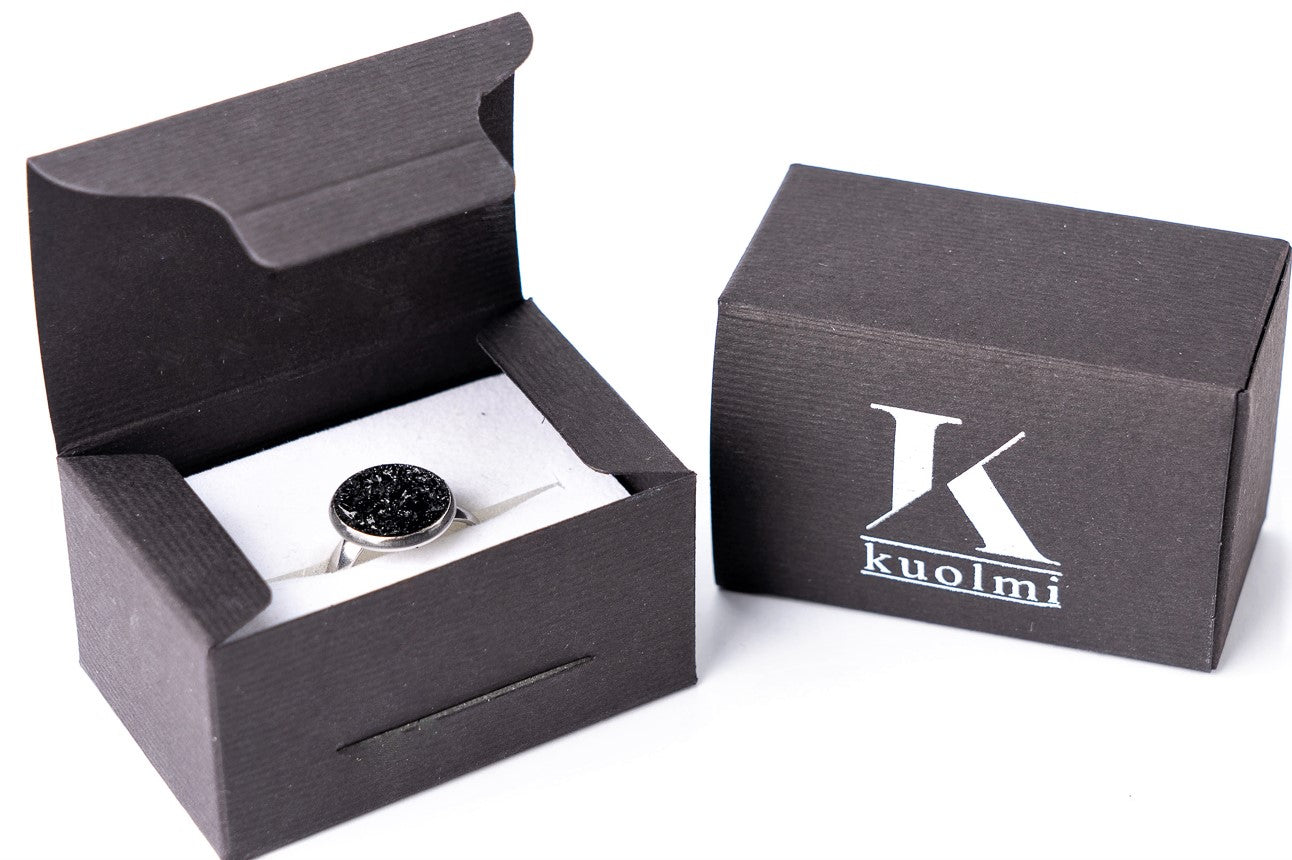 The KUOLMi handmade ring is a fantastic accessory that makes the look perfect. The 10 million-year-old stone will shine on your hand with all its brilliance. The ring is made of coal and stainless steel. It is adjustable in size. The image is symbolic because each piece is handmade, unrepeatable, and unique. The ring is packaged in gift packaging with an added description of the coal story.